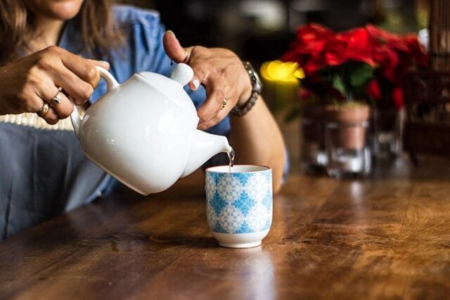 a woman pouring a cup of barley tea in the morning