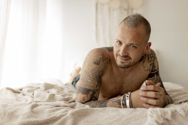 handsome man with tattoos withouth t-shirt in the bed in his room in Barcelona Spain
