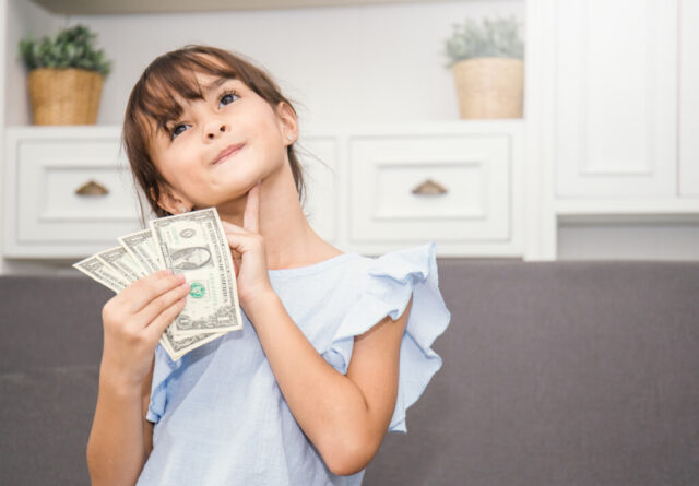 Cute little girl holding money in the living room, pretty girl t